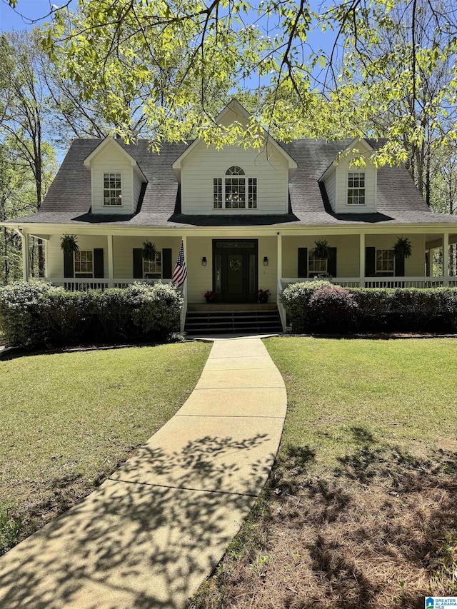 view of front of house with a shingled roof, covered porch, and a front lawn