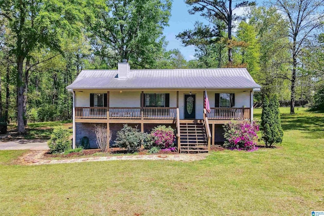 view of front of property with a front yard, metal roof, a chimney, and covered porch