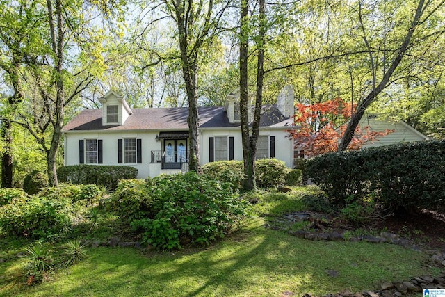 new england style home with stucco siding, french doors, and a front lawn