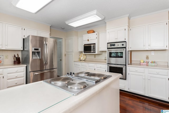 kitchen featuring ornamental molding, light countertops, white cabinetry, dark wood finished floors, and appliances with stainless steel finishes