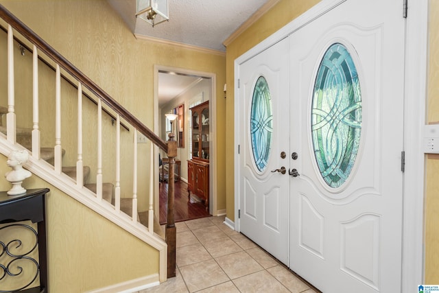 entryway with stairs, light tile patterned floors, a textured ceiling, and crown molding