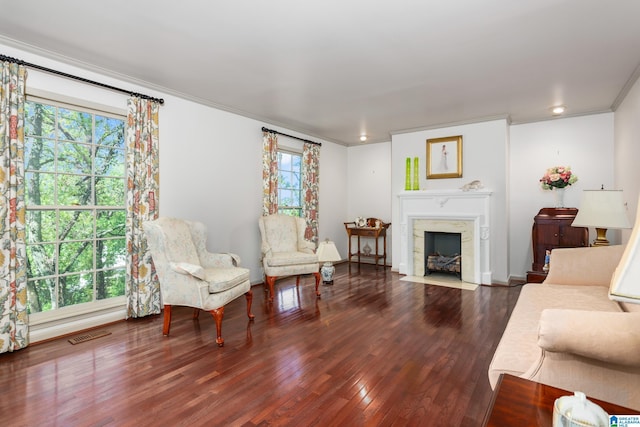 living room featuring a high end fireplace, visible vents, ornamental molding, and wood finished floors