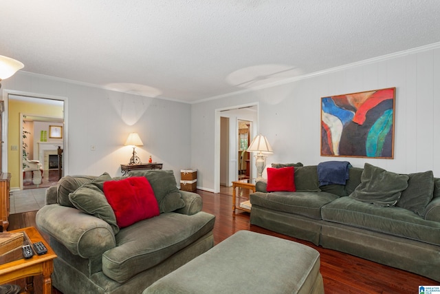 living room featuring crown molding, wood finished floors, baseboards, and a textured ceiling