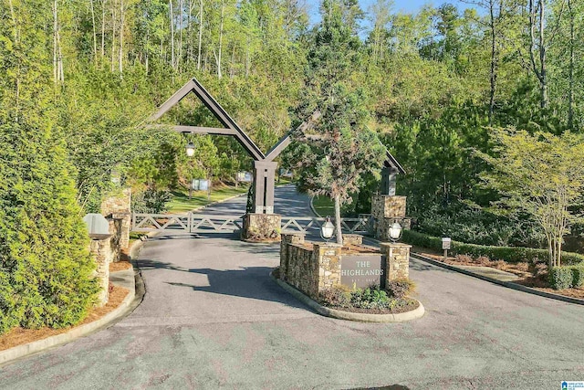 view of road with a gated entry, curbs, and a gate