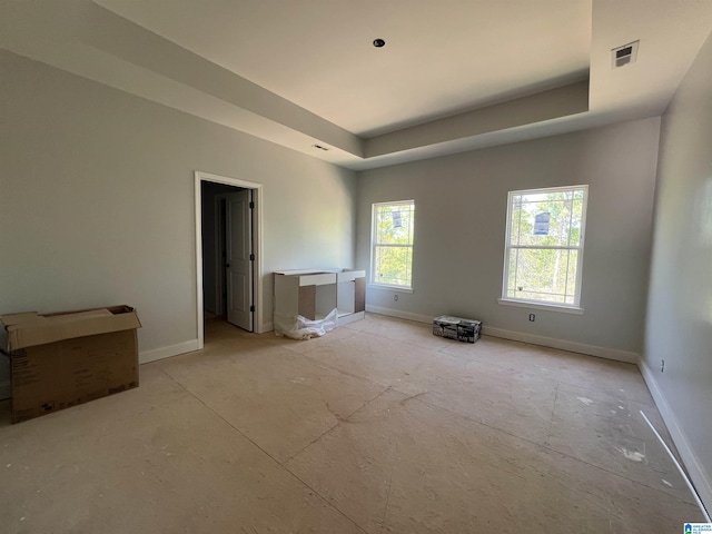 unfurnished bedroom with a tray ceiling, baseboards, and visible vents