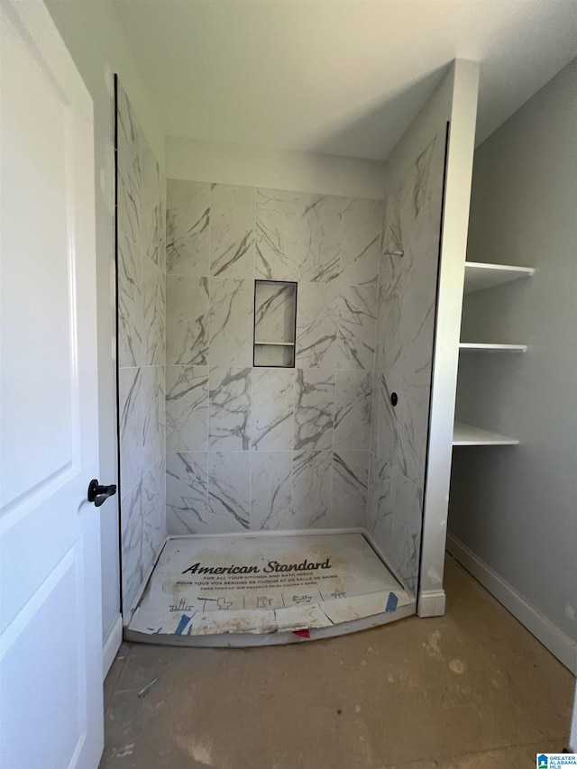 bathroom featuring tiled shower and baseboards