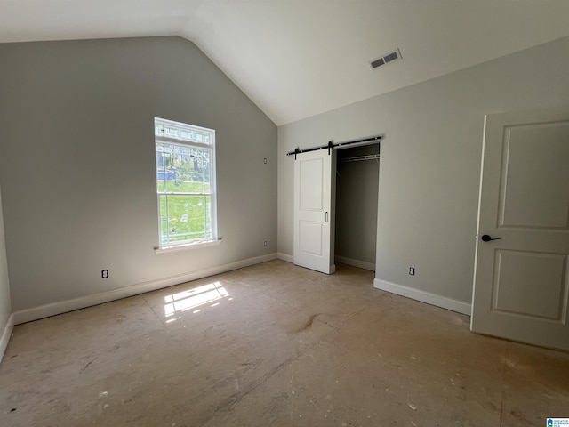 unfurnished bedroom featuring a barn door, visible vents, baseboards, and vaulted ceiling