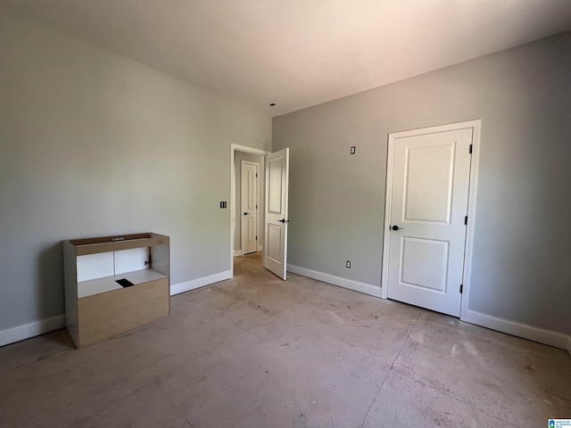 unfurnished bedroom featuring unfinished concrete floors and baseboards