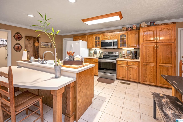 kitchen featuring stainless steel appliances, brown cabinetry, and crown molding