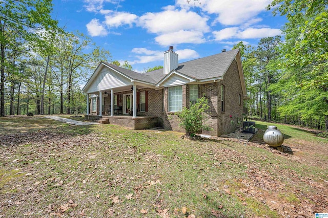 exterior space with brick siding, a ceiling fan, a yard, and a chimney