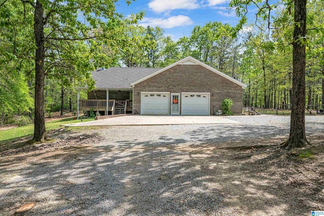 view of front of house featuring roof with shingles, a garage, gravel driveway, and brick siding