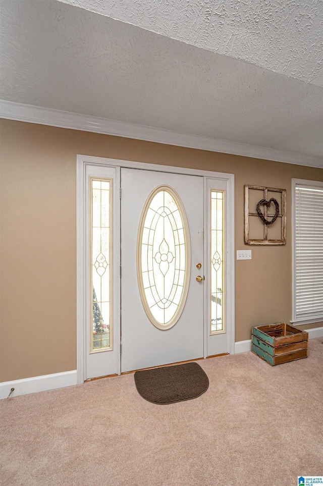 entrance foyer with baseboards, a textured ceiling, ornamental molding, and carpet floors