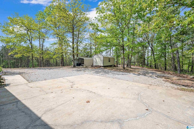 view of patio with a carport, driveway, an outbuilding, and a storage unit