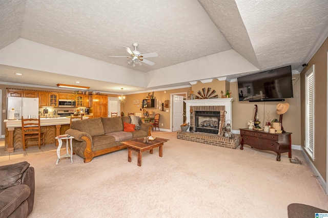 living area with ceiling fan with notable chandelier, a brick fireplace, light carpet, and a textured ceiling