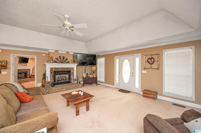 living area with baseboards, a fireplace, a ceiling fan, carpet floors, and visible vents