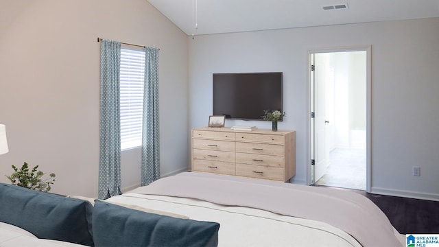 bedroom featuring baseboards, connected bathroom, visible vents, lofted ceiling, and wood finished floors