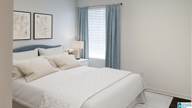 bedroom with wood finished floors, baseboards, and multiple windows