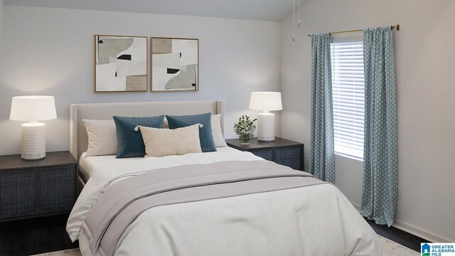 bedroom with baseboards, vaulted ceiling, and wood finished floors