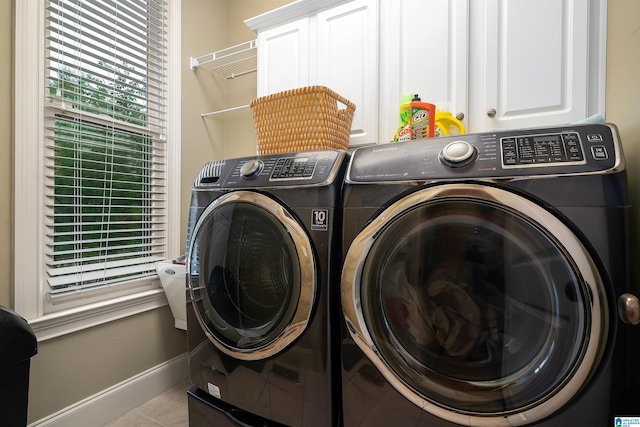 clothes washing area featuring cabinet space, tile patterned floors, washing machine and dryer, and baseboards