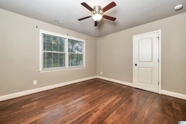 empty room featuring dark wood-style floors, baseboards, visible vents, and ceiling fan