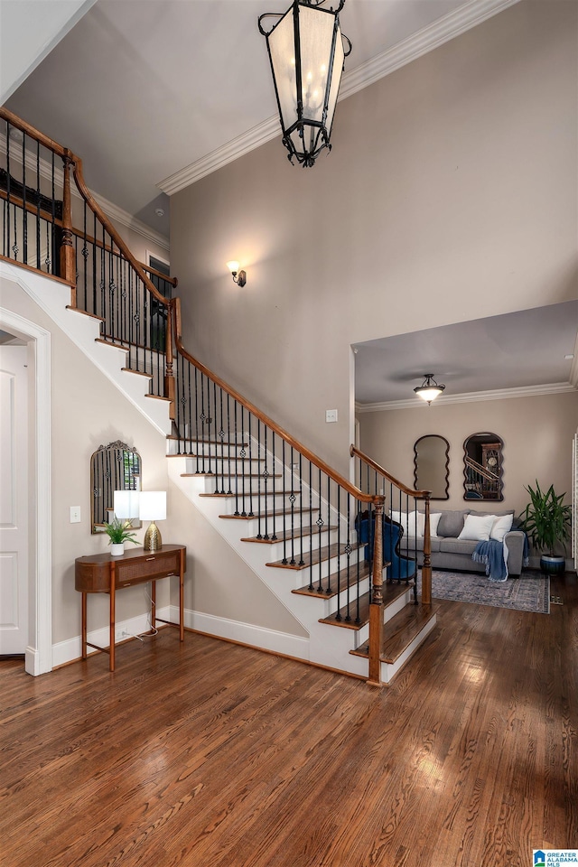 stairs with ornamental molding, baseboards, and wood finished floors