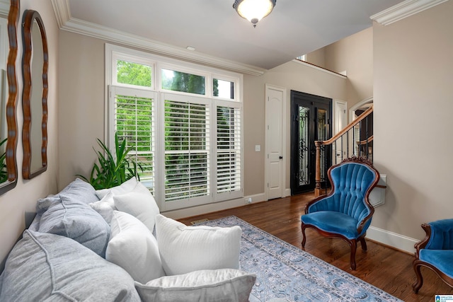 living area with baseboards, crown molding, and wood finished floors