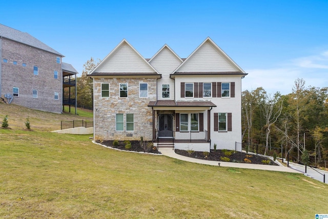 craftsman inspired home with a front lawn, fence, and stone siding