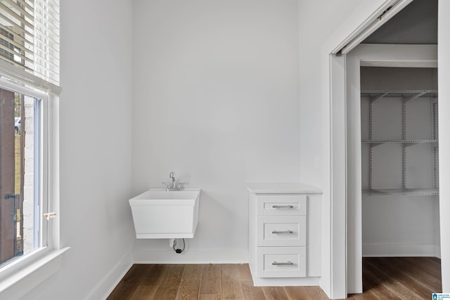 bathroom featuring wood finished floors, a sink, and baseboards