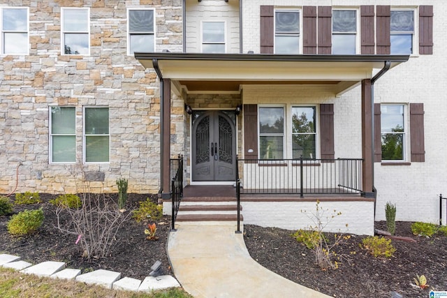 view of exterior entry with french doors, stone siding, and brick siding