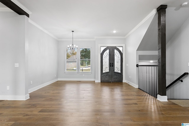 foyer entrance featuring ornamental molding, wood finished floors, french doors, baseboards, and a notable chandelier