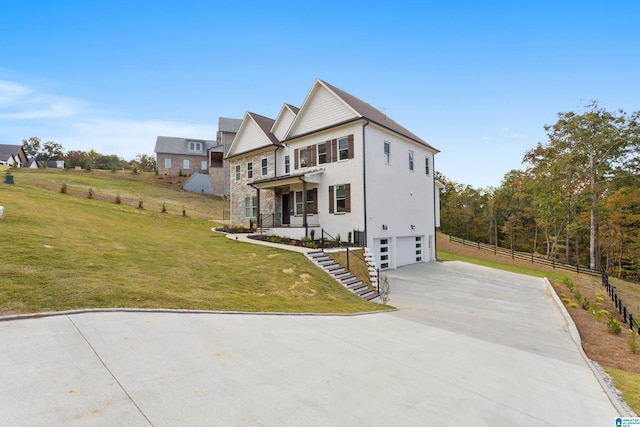 view of front of property with a front yard, an attached garage, stone siding, fence, and concrete driveway