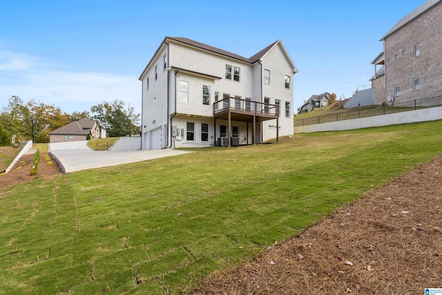 rear view of property featuring a yard, stucco siding, fence, an attached garage, and concrete driveway
