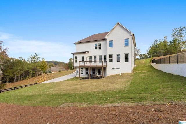 back of property with fence, a wooden deck, a lawn, and stucco siding