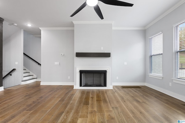 unfurnished living room with wood finished floors, ornamental molding, and a ceiling fan