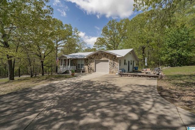 view of front facade with a porch, stone siding, a garage, and driveway