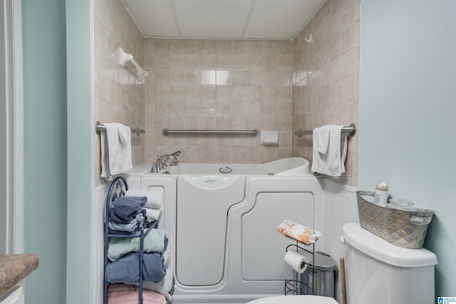 bathroom with a tub to relax in and toilet