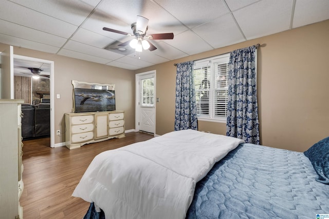 bedroom featuring baseboards, a paneled ceiling, ceiling fan, and wood finished floors