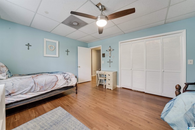 bedroom featuring a closet, ceiling fan, a drop ceiling, and wood finished floors