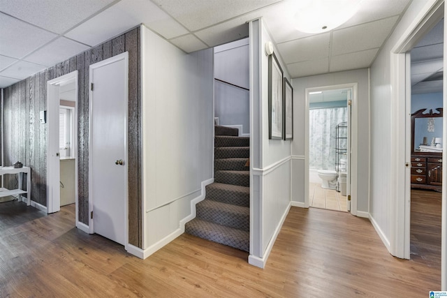 staircase with a drop ceiling and wood finished floors