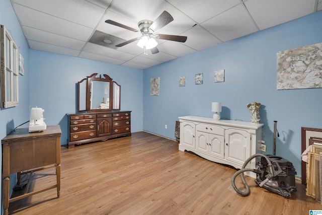 bedroom featuring light wood-style floors, a drop ceiling, and a ceiling fan