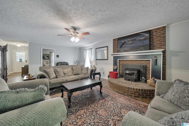 living area with wood finished floors, a wood stove, plenty of natural light, and a wainscoted wall