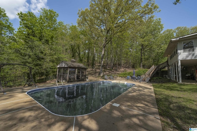 view of swimming pool featuring a yard, a gazebo, stairway, fence, and a fenced in pool