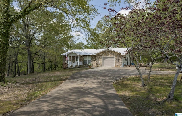 view of front of home featuring an attached garage, aphalt driveway, and stone siding
