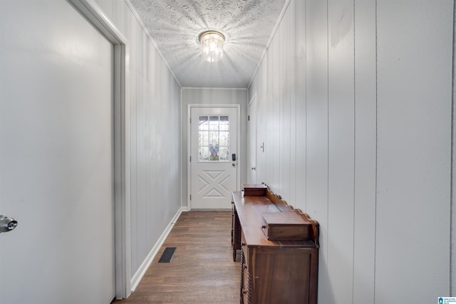 doorway with ornamental molding, baseboards, visible vents, and dark wood finished floors