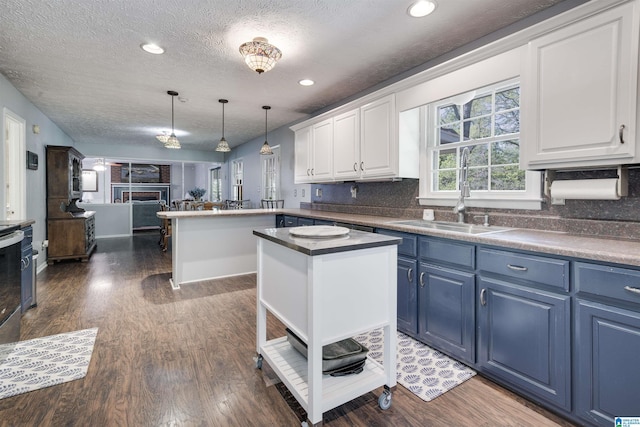 kitchen with a fireplace, dark wood finished floors, white cabinetry, pendant lighting, and blue cabinets