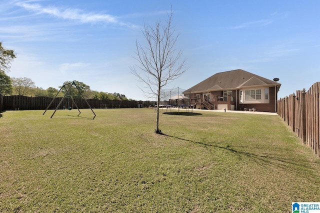 view of yard with a trampoline, a fenced backyard, a playground, and a patio area