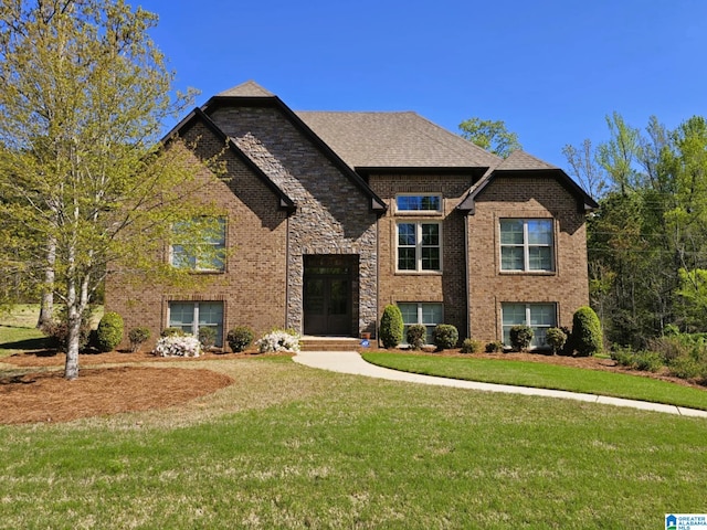view of front of home with stone siding, a front lawn, and brick siding