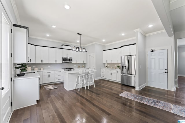 kitchen with a kitchen breakfast bar, a center island, light countertops, stainless steel appliances, and dark wood-style floors
