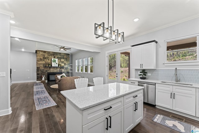 kitchen with a sink, a ceiling fan, a fireplace, crown molding, and stainless steel dishwasher