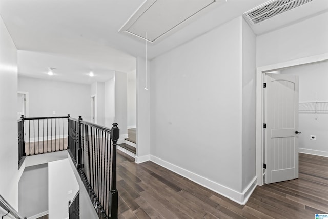 hall with an upstairs landing, visible vents, attic access, and wood finished floors